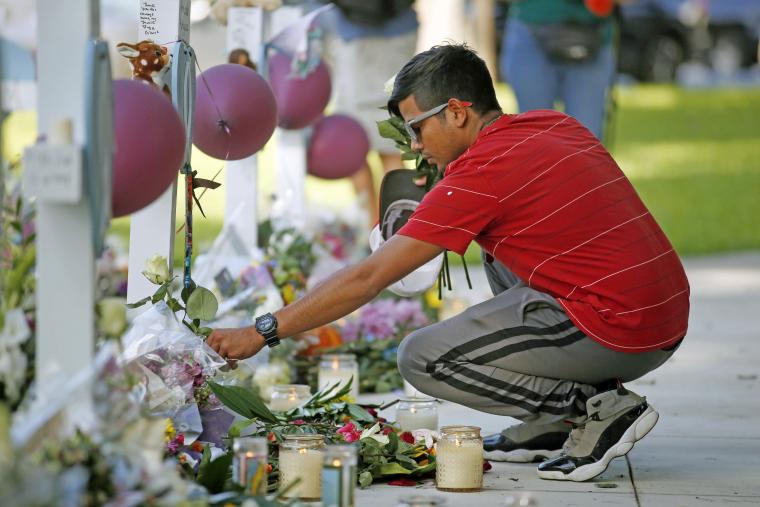 A man laying flowers at school shooting memorial.